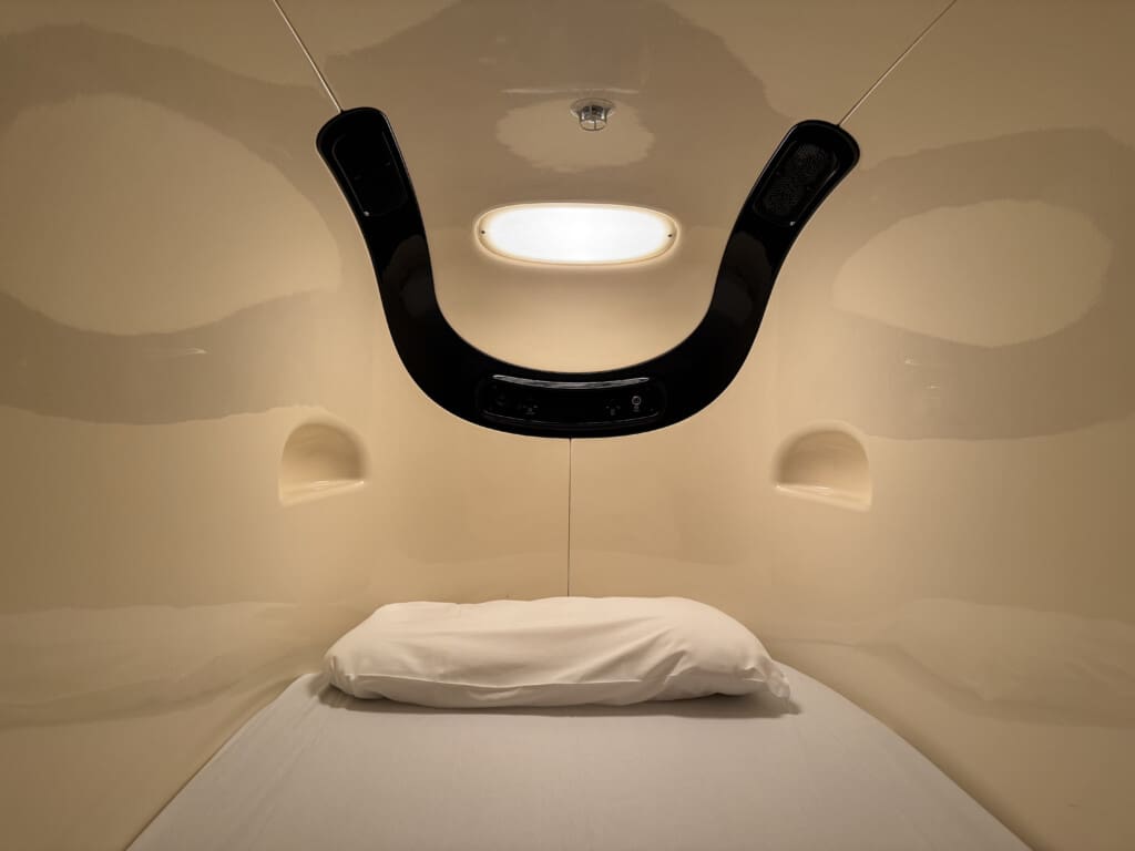 a bed with a white pillow and a black object from the ceiling