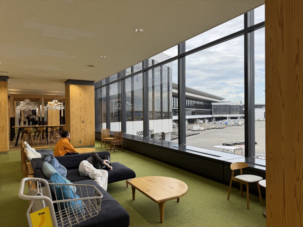 a room with a large window and a couple of people sitting on couches