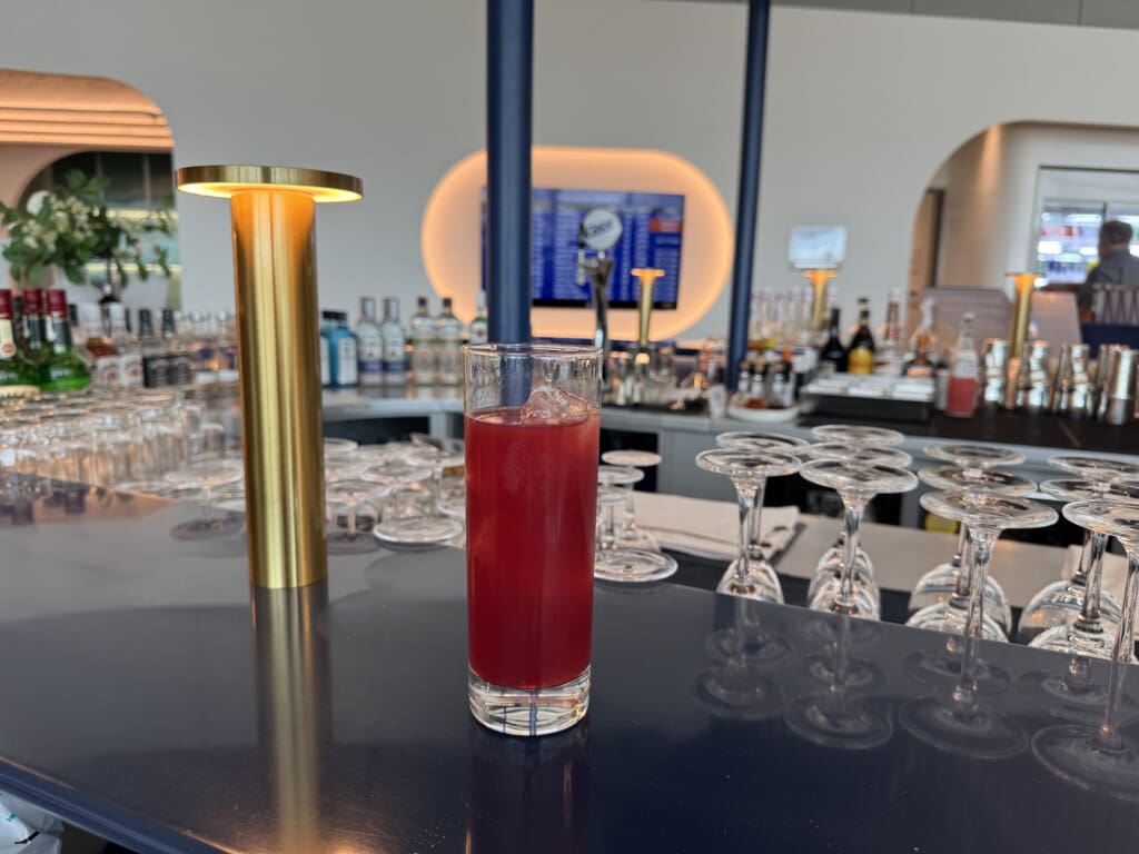 a glass of red liquid on a bar