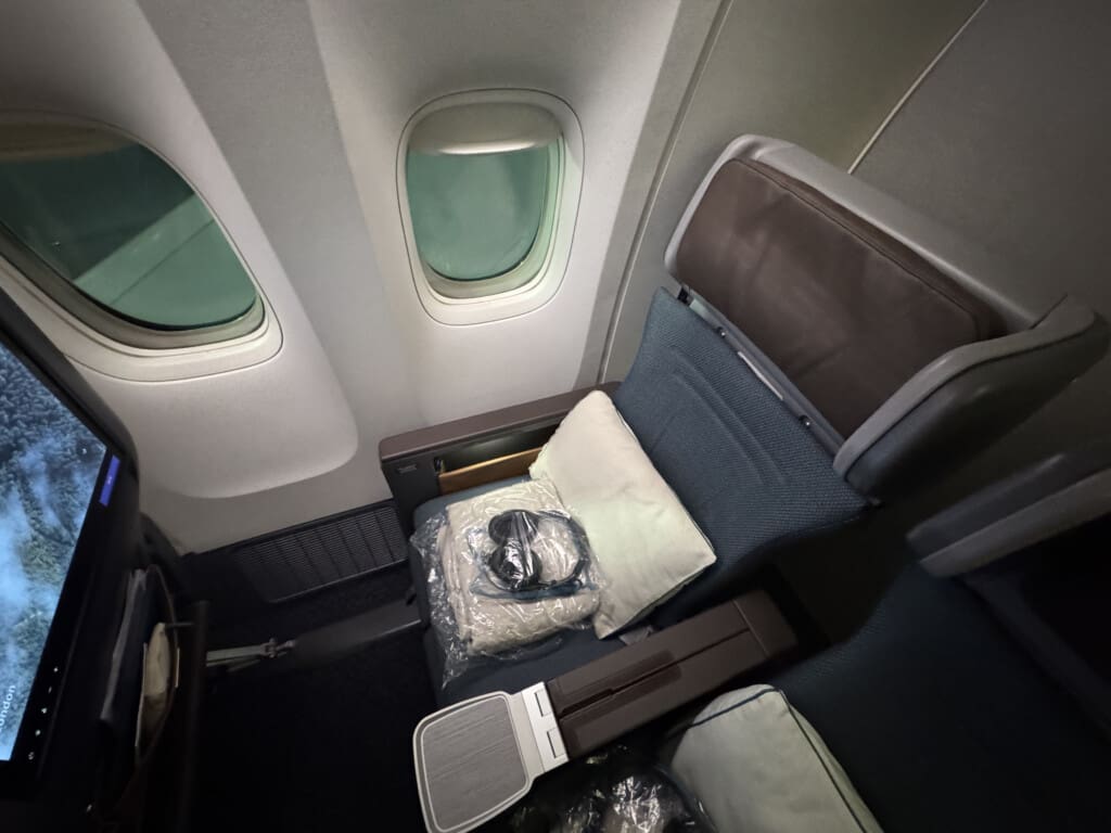 an airplane seat with a pillow and a bag on it