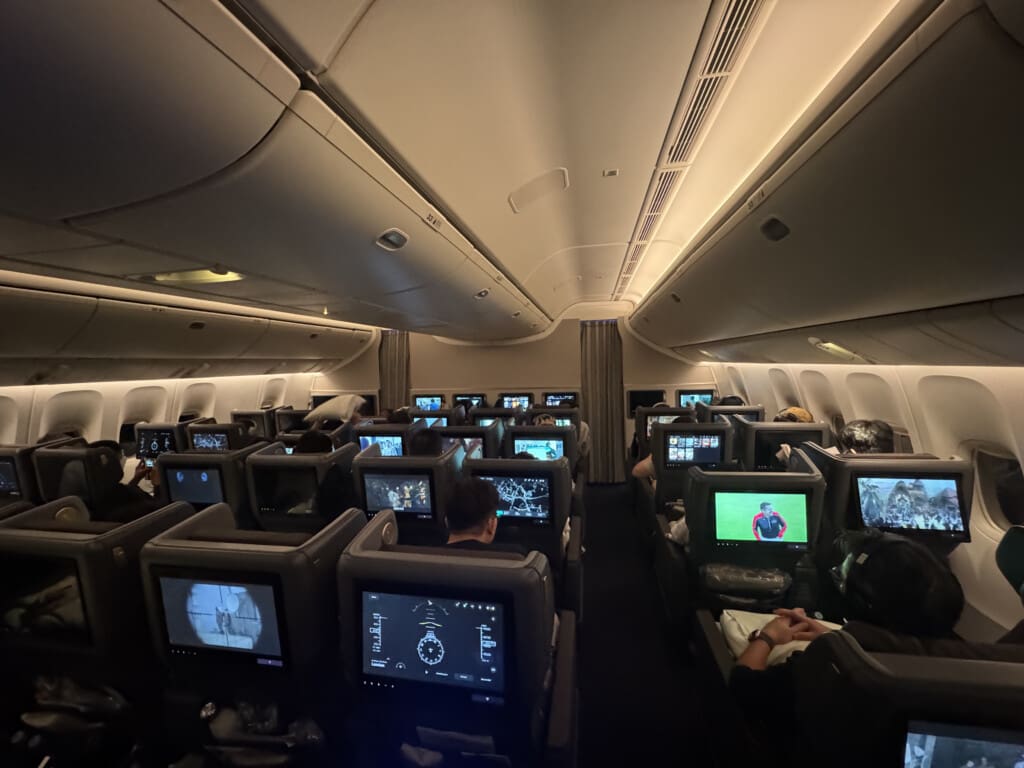 a group of people sitting in an airplane with monitors