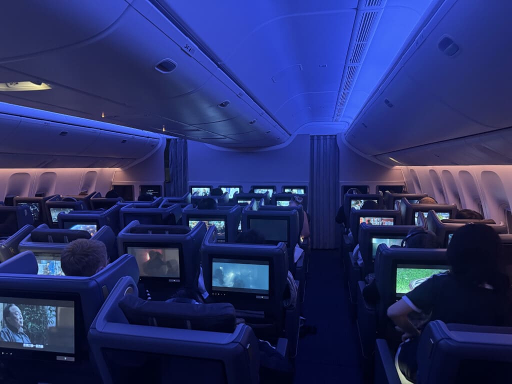 a group of people sitting in an airplane with monitors