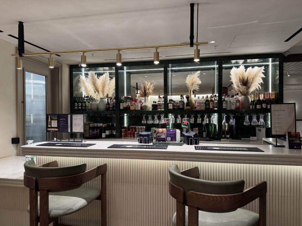 a bar with chairs and a shelf with bottles