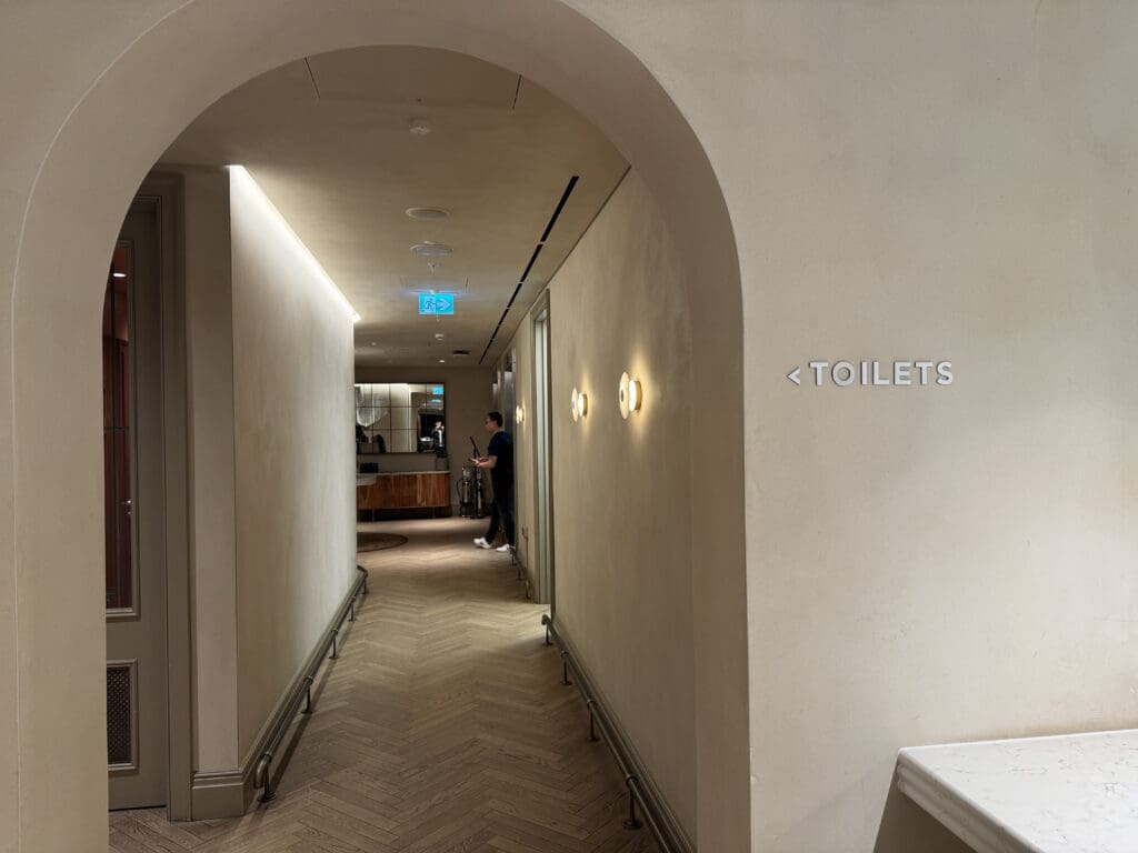 a hallway with a sign and a man standing in the background