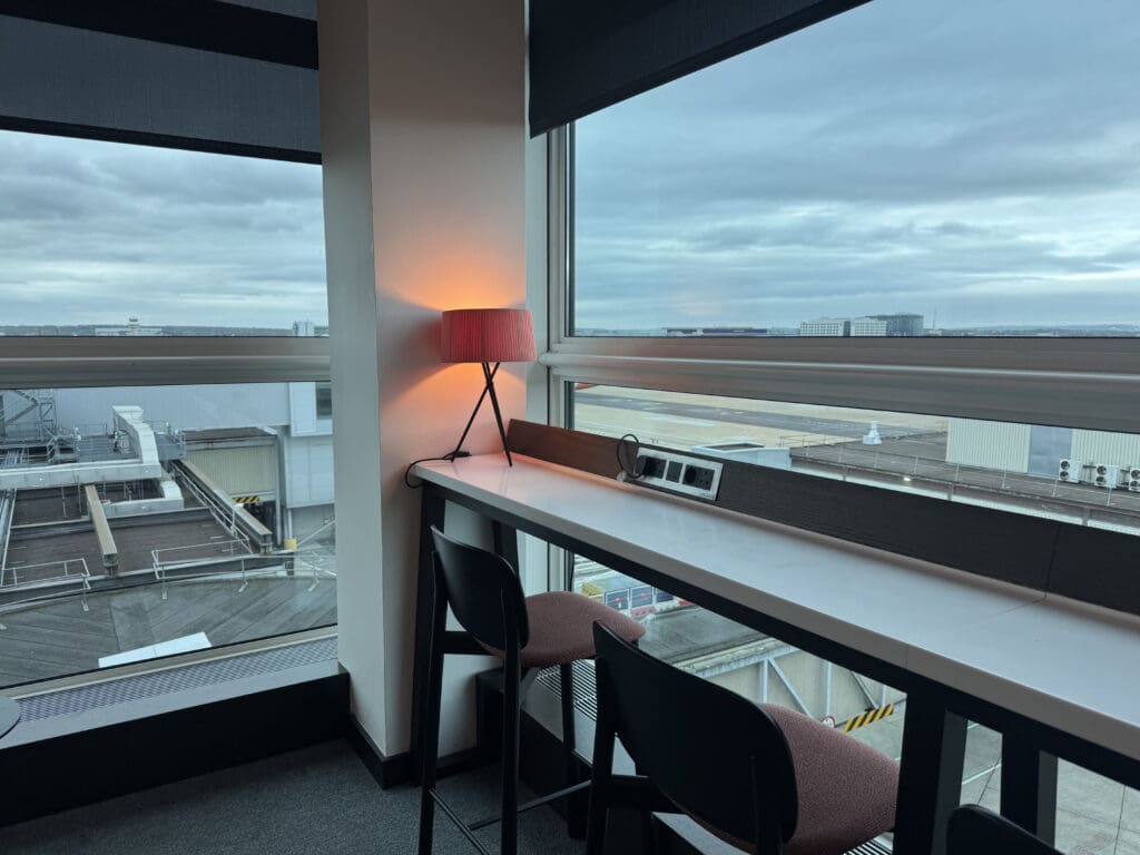 a table with a red lamp and chairs in a room with a window