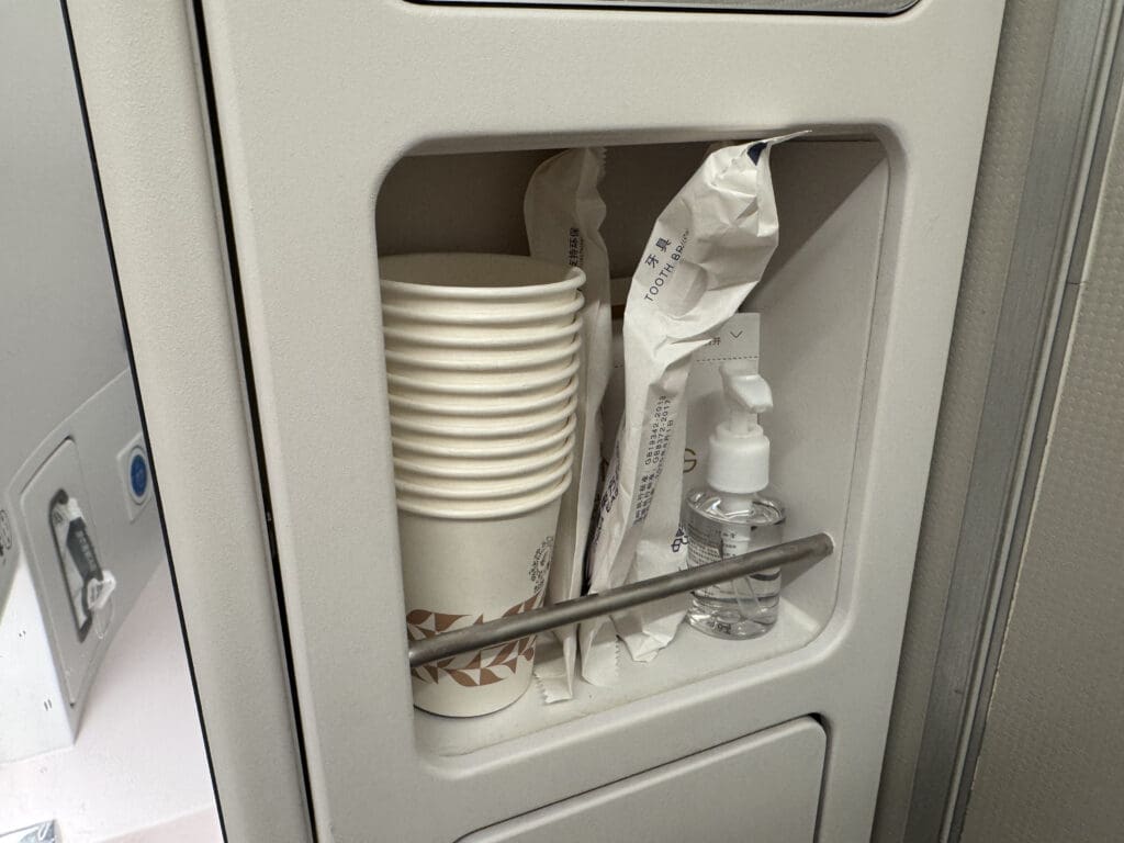 a small cabinet with a stack of cups and a bottle of liquid