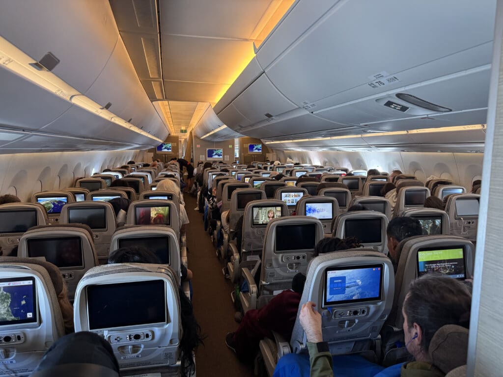 a group of people sitting in an airplane with monitors