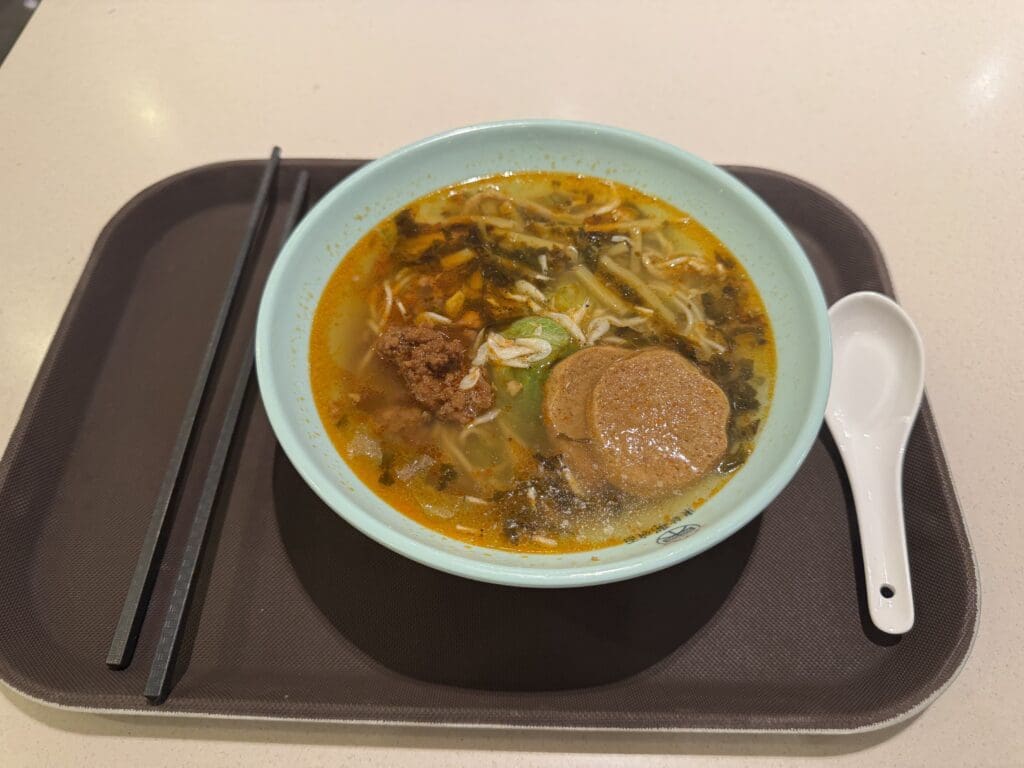 a bowl of soup with chopsticks on a tray