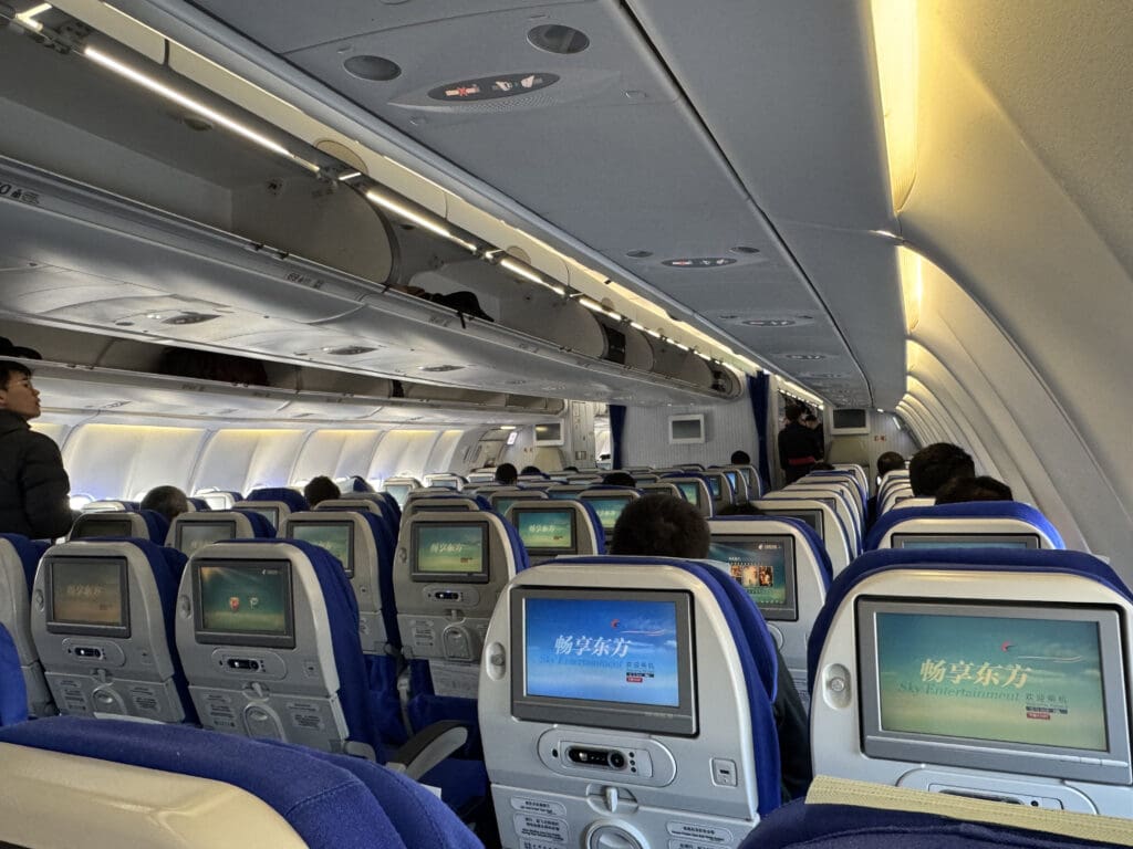 a row of seats with monitors on the side of the plane