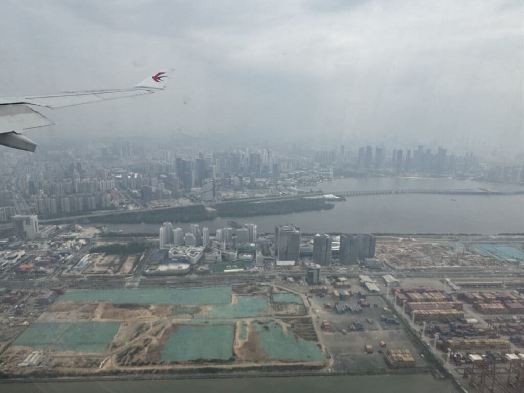 a plane wing in the air with a city in the background