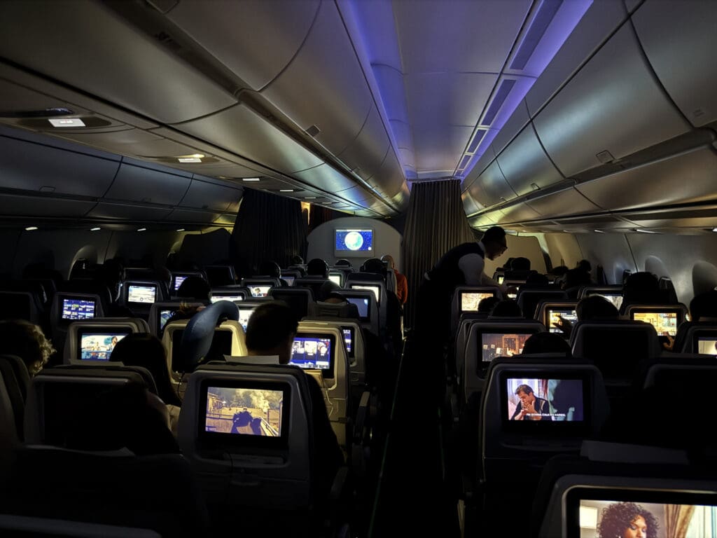 a group of people sitting in an airplane with monitors