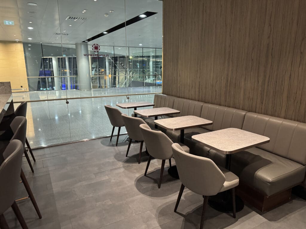 a booth seating with tables and chairs in a room with glass walls