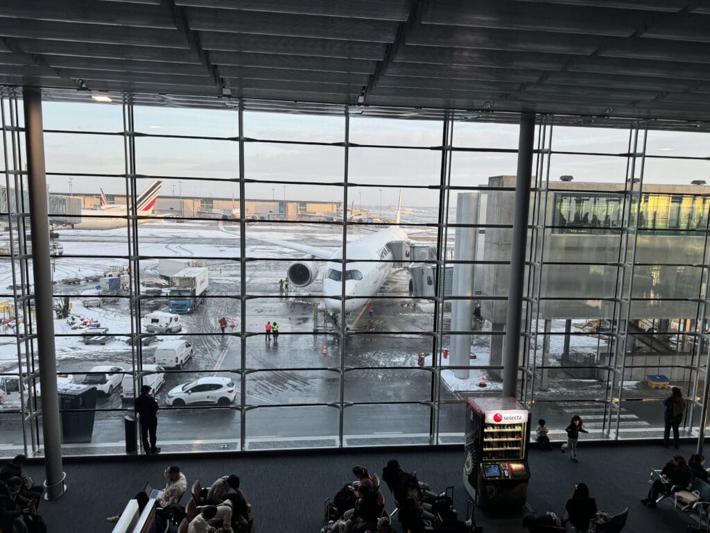 a large glass window with people walking and a plane in the background