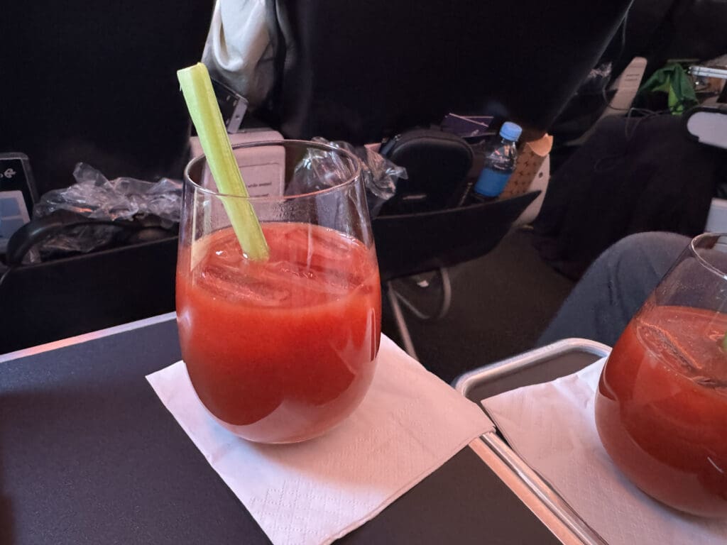 a glass of red liquid with a green stem and a straw