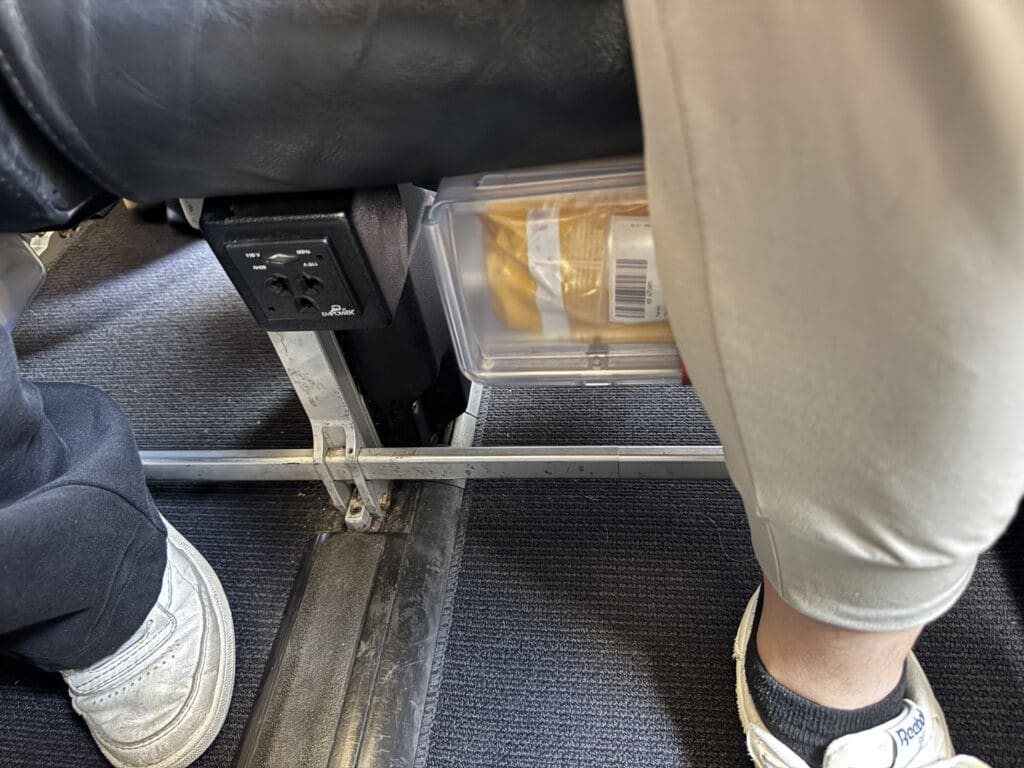 a person's feet in a plastic container under a chair