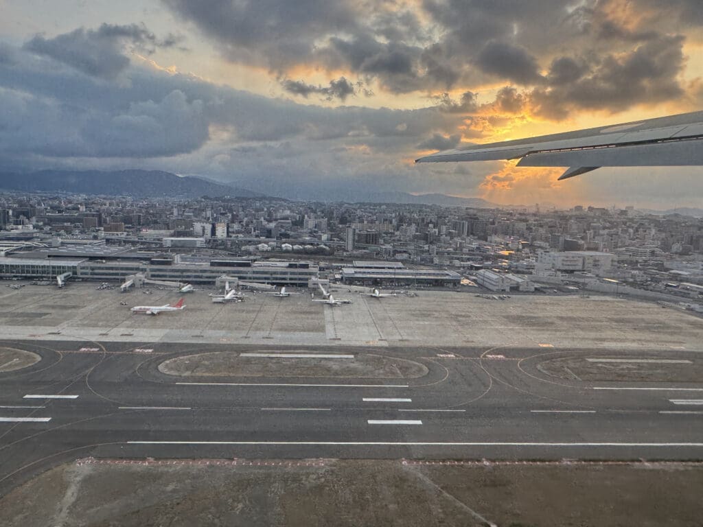 an airplane wing on a runway with a city in the background